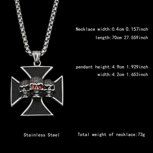 Macro view of gothic steel cross pendant with three skulls and red gems on black background