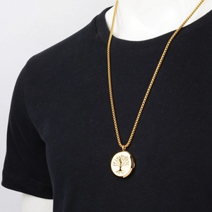 Close-up of golden tree of life disc pendant necklace on black shirt with square pearl chain
