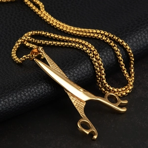 Macro shot of gold scissor pendant with textured handle and thick square box chain