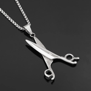 Macro shot of silver scissor pendant with textured cross-pattern handle on box chain