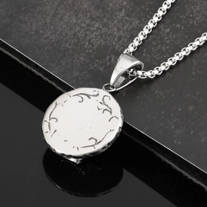 Detailed macro view of an industrial skull emblem on a polished titanium steel pendant