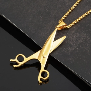 Macro detail of golden scissor pendant on ball chain with polished metallic texture