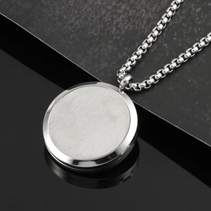 Macro shot of silver round titanium steel pendant with brushed and polished textures