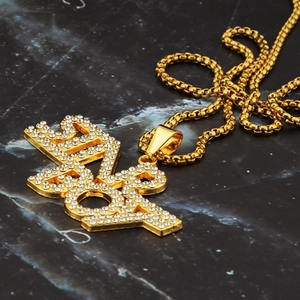 Detailed close-up of iced-out gold BAD BOY letter pendant with white rhinestones