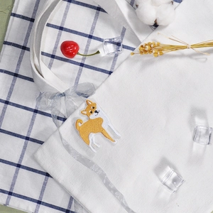 White canvas tote bag featuring Shiba Inu embroidery and blue ribbon on plaid backdrop