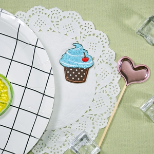 Écusson brodé cupcake avec glaçage bleu et cerise rouge sur assiette décorative