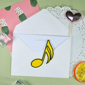 Yellow musical note embroidered patch for DIY clothing and accessories on a white envelope