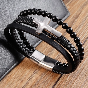 Dettaglio del bracciale multistrato in pelle nera da uomo con croce d'argento e chiusura
