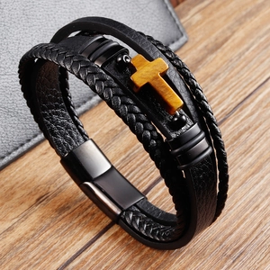 Dettaglio bracciale in pelle da uomo con cordino nero intrecciato e croce in legno giallo