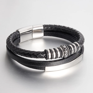 Detail of men's braided leather bracelet with engraved silver metal charm and magnetic clasp