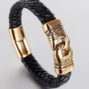 Close-up of men's black braided leather bracelet with golden totem engraved metal clasp