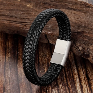Men's black braided leather bracelet with silver magnetic buckle on dark wood background