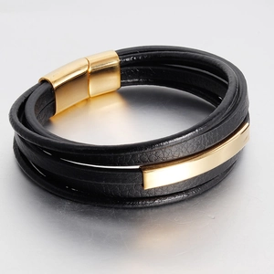 Detail of multi-layered black leather bracelet with golden magnetic buckle and metal bar