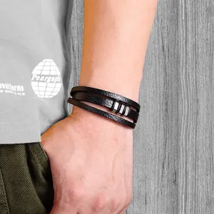 Gros plan d'un bracelet multicouche en cuir tressé noir avec cylindres en argent sur le poignet