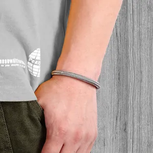Détail macro du bracelet en acier inoxydable pour homme avec texture tissée au poignet