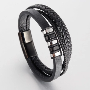 Detail of multilayered black leather bracelet with braided cords and silver metal rings