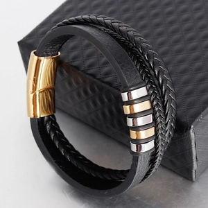 Detail of multi-layer black leather bracelet with silver and gold metal rings and clasp