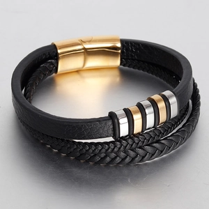 Detail of multi-layer braided leather bracelet with gold and silver rings and magnetic clasp