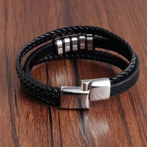 Detail of men's multilayer braided leather bracelet with silver metal magnetic clasp on wood