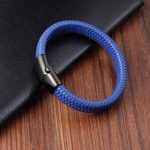 Blue braided leather bracelet for men with black magnetic clasp on a wooden desk