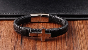 Detailed macro view of black braided leather bracelet with silver cross and magnetic clasp