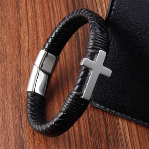 Men's braided black leather bracelet with silver stainless steel cross on wood background