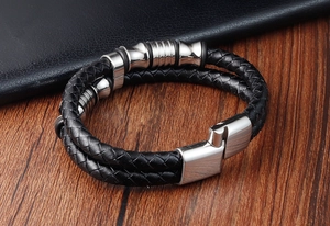 Dettaglio del bracciale in pelle intrecciata nera da uomo con anelli in acciaio e chiusura