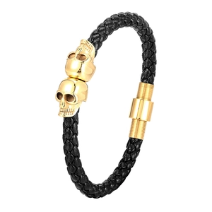Men's braided black leather bracelet with two gold skull charms and polished metal clasp