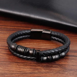 Dettaglio del bracciale in pelle intrecciata nera a due strati con chiusura magnetica e perle