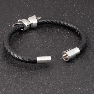 Close-up of black braided leather bracelet with silver skull charms and a metal screw clasp