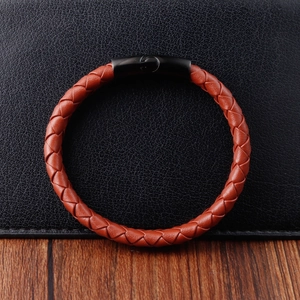 Detail of red-brown braided leather bracelet with matte black magnetic metal clasp
