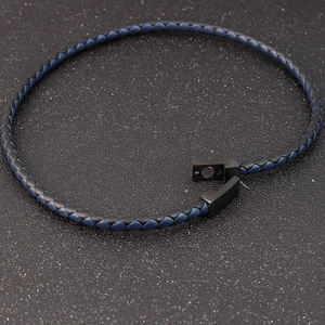 Détail d'un bracelet en cuir tressé bleu et noir avec un fermoir magnétique noir mat