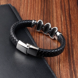 Detail of black braided leather bracelet with stainless steel magnetic clasp and metal accents