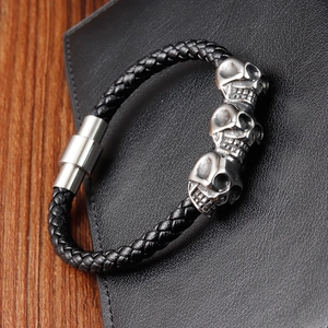 Close-up of punk style braided leather bracelet with silver skull charms and magnetic clasp