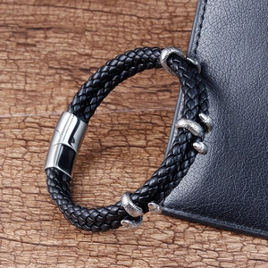 Détail du bracelet en cuir tressé noir avec anneaux dragon sur fond en bois