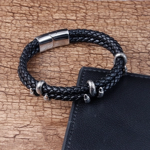 Bracelet tressé en cuir noir pour homme avec fermoir magnétique argenté sur fond bois