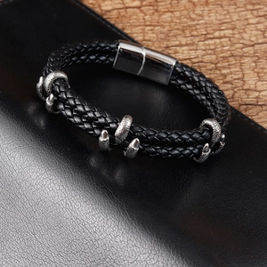 Détail d'un bracelet en cuir tressé noir avec charme de griffe de dragon argentée et fermoir magnétique