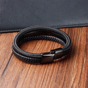 Dettaglio di un bracciale multistrato in pelle intrecciata nera con chiusura in acciaio