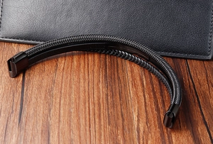 Dettaglio di un bracciale in pelle intrecciata nera da uomo con chiusura magnetica