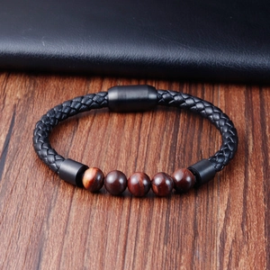 Detail of multi-layer braided leather bracelet with red tiger eye beads on wooden surface