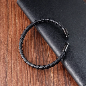 Minimalist black braided leather titanium steel bracelet for men on a wooden table