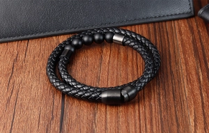 Detail of men's double-layer braided leather bracelet with black matte beads on wood
