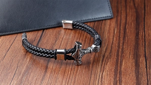 Detailed close-up of a men's braided black leather bracelet with Thor's Hammer Mjolnir charm