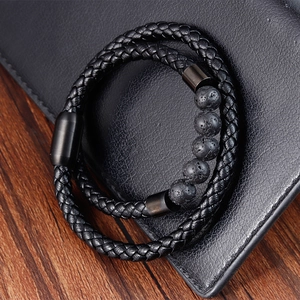 Macro detail of men's braided leather bracelet with natural lava stone beads and magnetic clasp