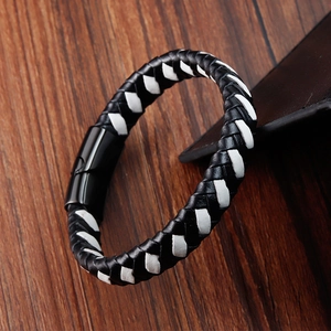 Détail d'un bracelet en cuir tressé noir et blanc avec fermoir magnétique en métal mat
