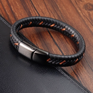 Close-up of men's woven black leather bracelet with magnetic clasp on wood surface