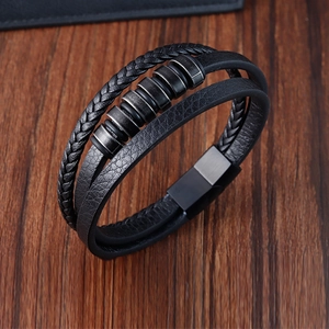 Detalle de una pulsera multicapa de cuero negro con anillos metálicos sobre madera