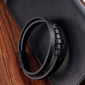 Detalle de pulsera de cuero negro de varias capas con anillos metálicos y textura