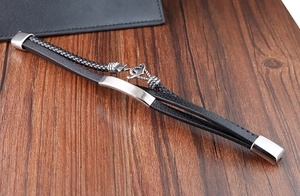 Multilayer black leather anchor bracelet with silver magnetic buckle on wood surface