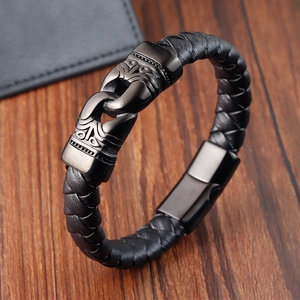 Braided black leather bracelet for men with engraved dark gray metal buckle on wood